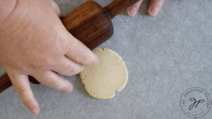 A piece of dough rolled flat on a piece of parchment paper.