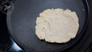 An oat flour flatbread cooking on a skillet.