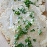 A close up of oat flour flatbread covered in melted garlic butter and fresh parsley.