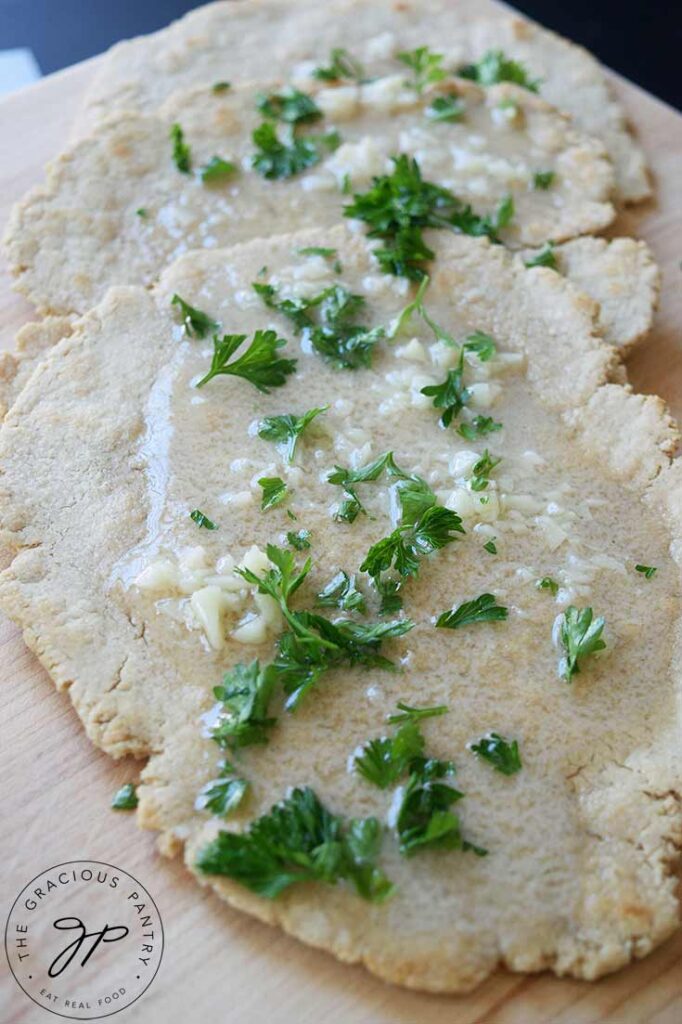A close up of oat flour flatbread covered in melted garlic butter and fresh parsley.