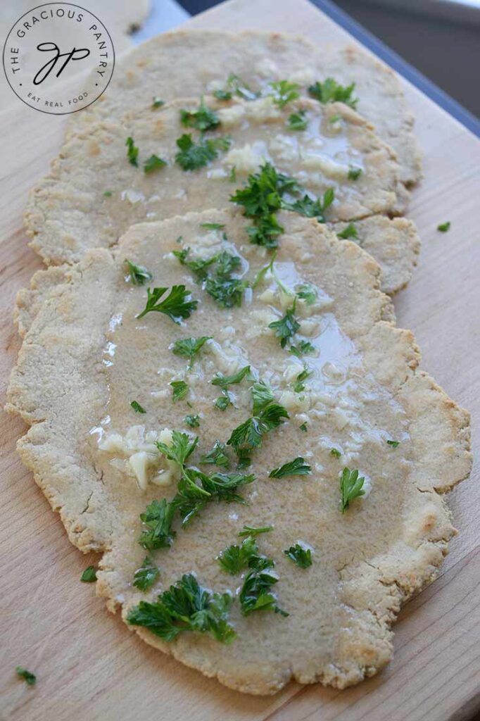 An overhead view of oat flour flatbreads covered in melted garlic butter and fresh parsley.