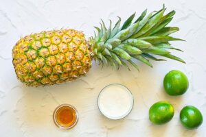All the ingredients for this Pineapple Popsicles Recipe laying on a white surface.