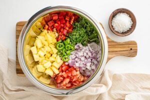 All the ingredients for pineapple salsa sitting, unmixed, in a mixing bowl.