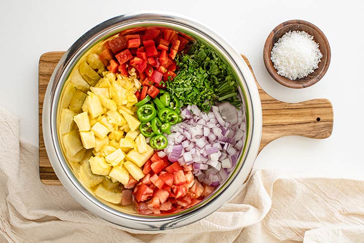 All the ingredients for pineapple salsa sitting, unmixed, in a mixing bowl.