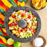 An overhead view of a stone salsa bowl holding pineapple salsa.