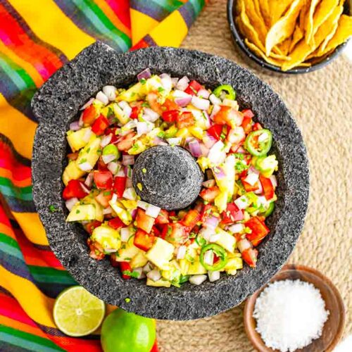 An overhead view of a stone salsa bowl holding pineapple salsa.