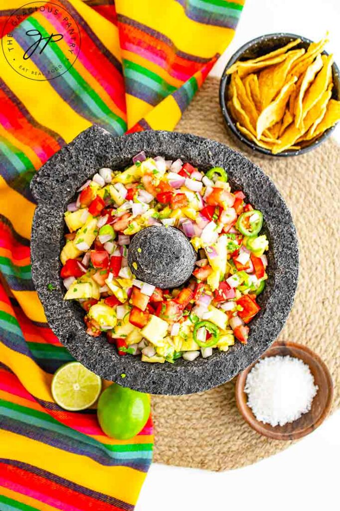 An overhead view of a stone salsa bowl holding pineapple salsa.