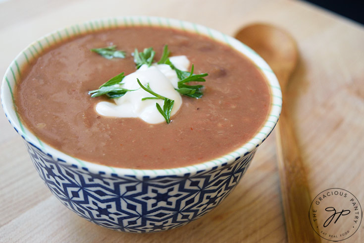 Refried Bean Soup served in a small, decorative bowl, garnished with plain yogurt and fresh cilantro.