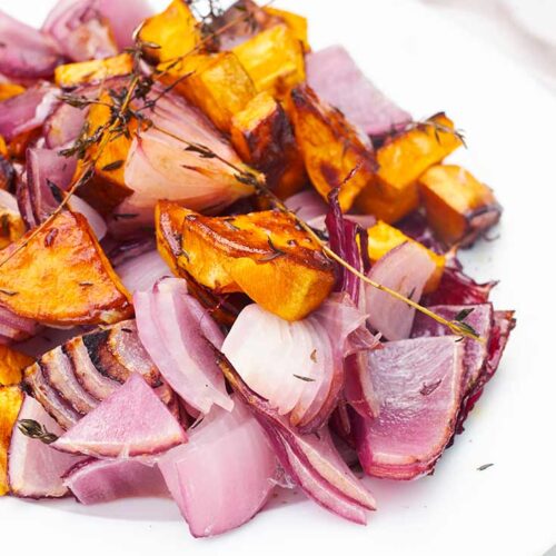 A side view of a white plate holding Herb And Garlic Roasted Sweet Potato Salad.