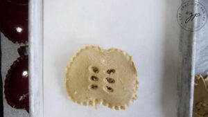 An unbaked Apple Hand Pie sitting on a parchment lined cookie sheet.