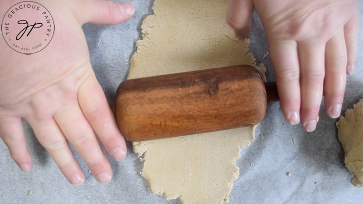 Rolling out pie crust dough with a wooden rolling pin.