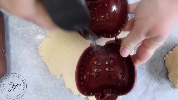 Spraying a hand pie form with an oil sprayer.