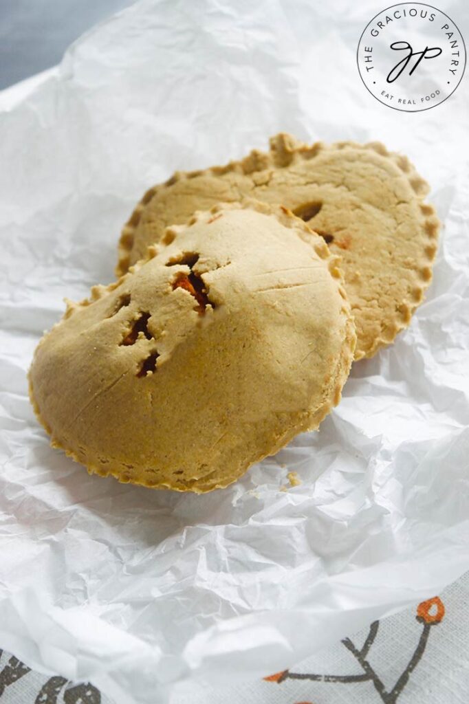 Two hand pies laying on a piece of parchment paper.