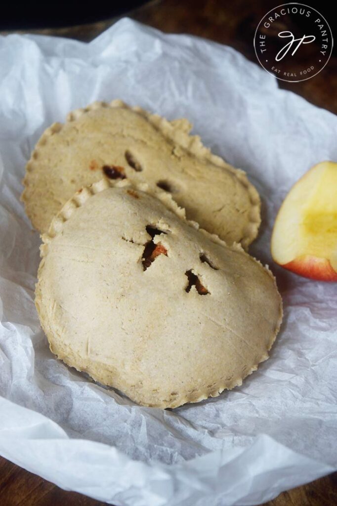 An up close view of two Apple Hand Pies laying on a piece of parchment paper.