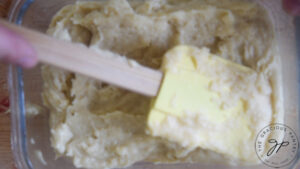 Spreading out Chickpea Tofu batter with a spatula in a glass dish.