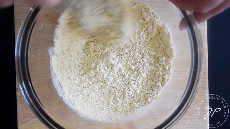 Whisking salt with chickpea flour in a glass mixing bowl.