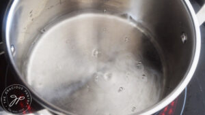 A pot of water simmers on a stove top.