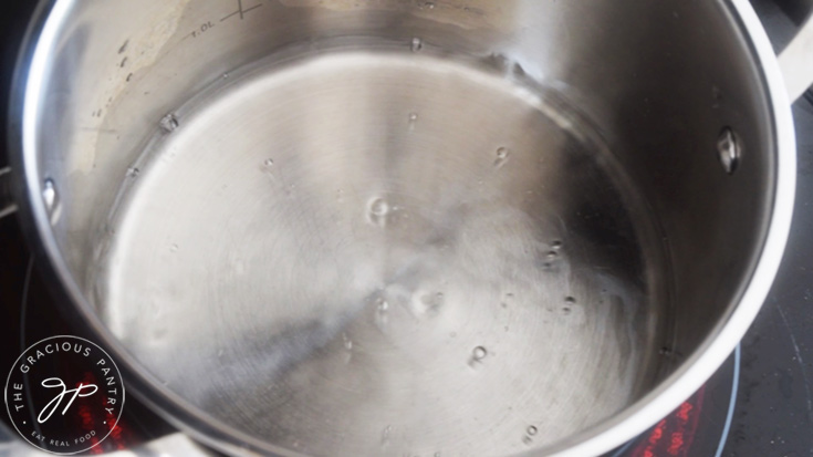 A pot of water simmers on a stove top.