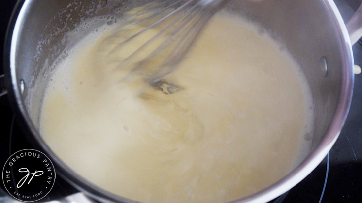 Whisking Chickpea Tofu batter into simmering water in a pot.
