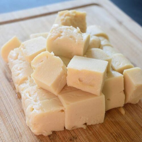 Cubes of Chickpea Tofu sit gathered on a wooden cutting board.