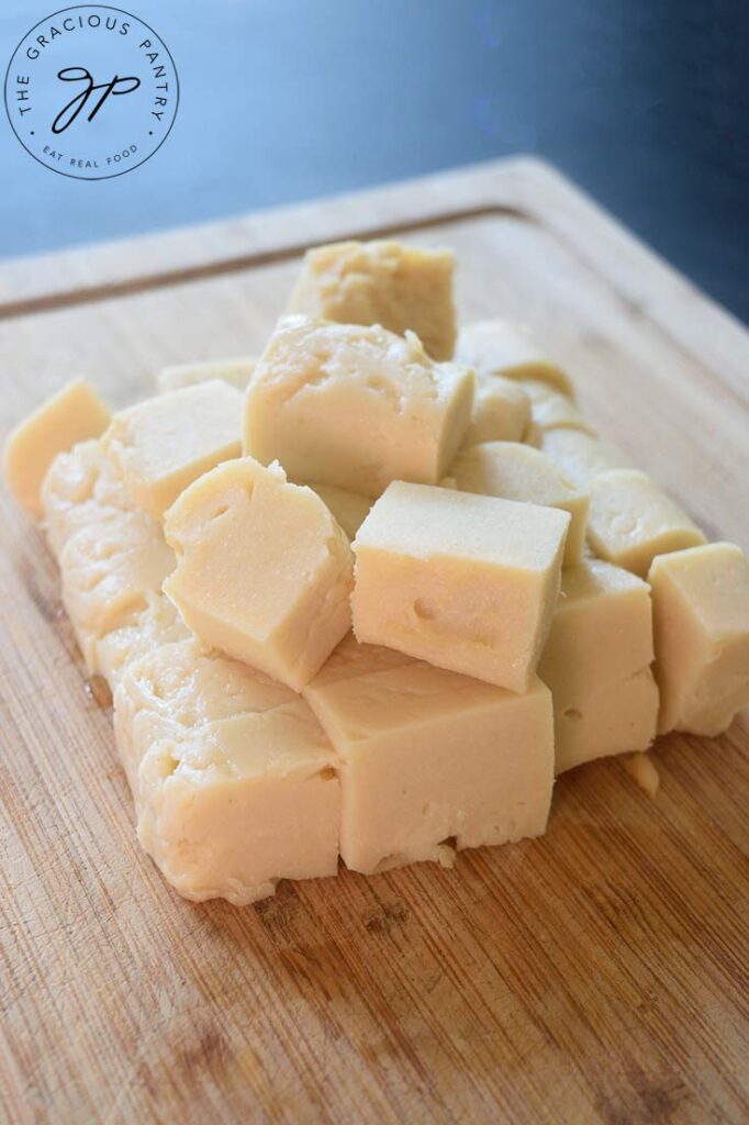 Cubes of Chickpea Tofu sit gathered on a wooden cutting board.