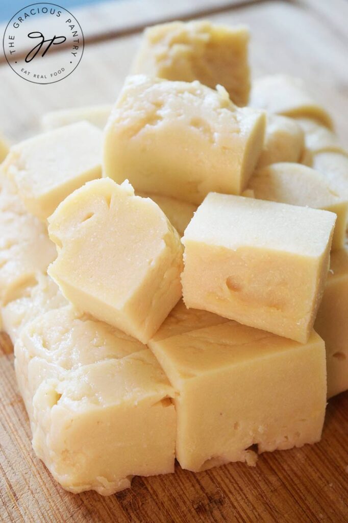 A closeup view of cubed chickpea tofu gathered on a wood cutting board.