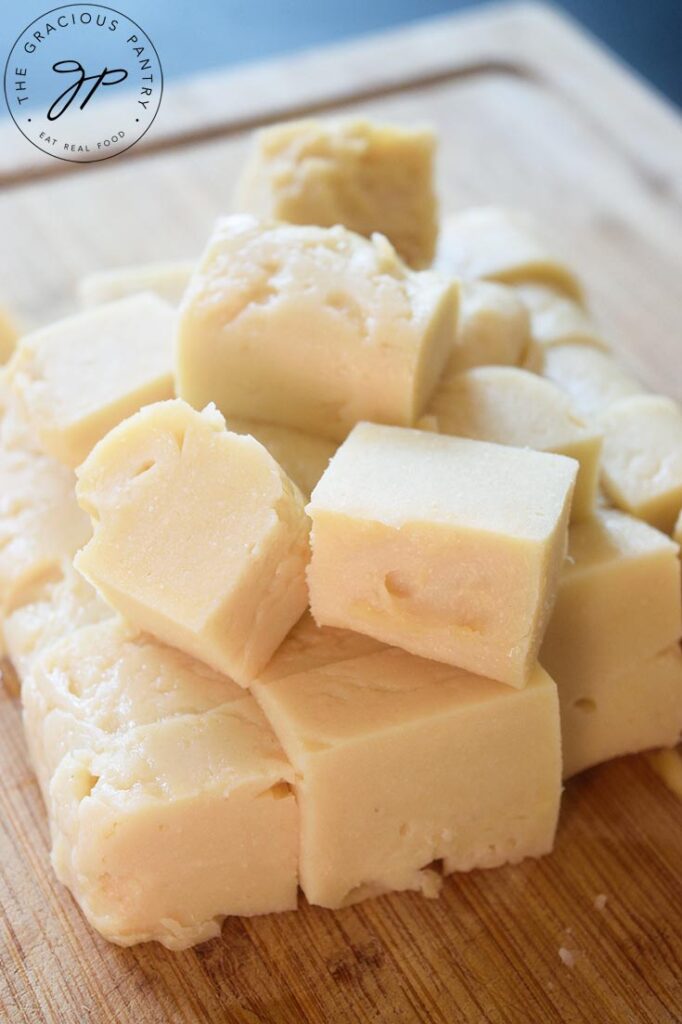 A side view of chickpea tofu cut into cubes and gathered on a wood cutting baord.
