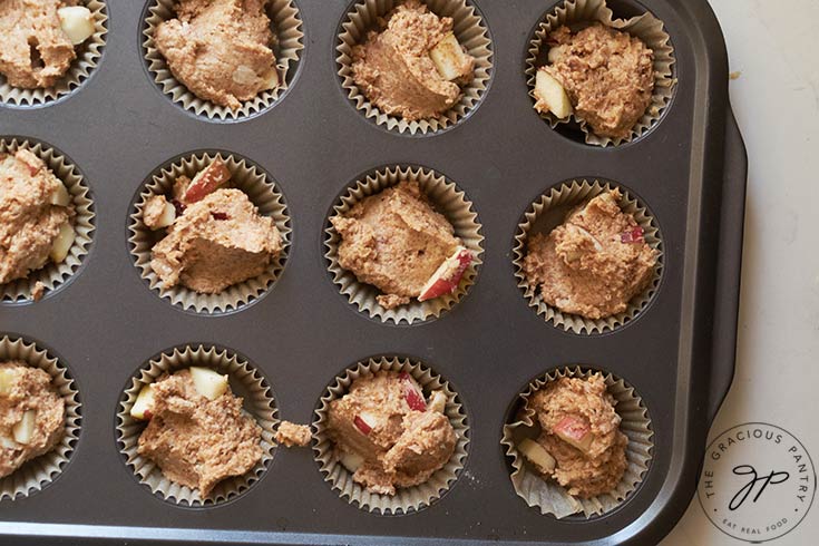 Cinnamon Apple Muffins batter scooped into a muffin pan.