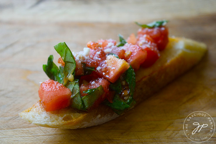 A single Classic Bruschetta sitting on a wooden surface.