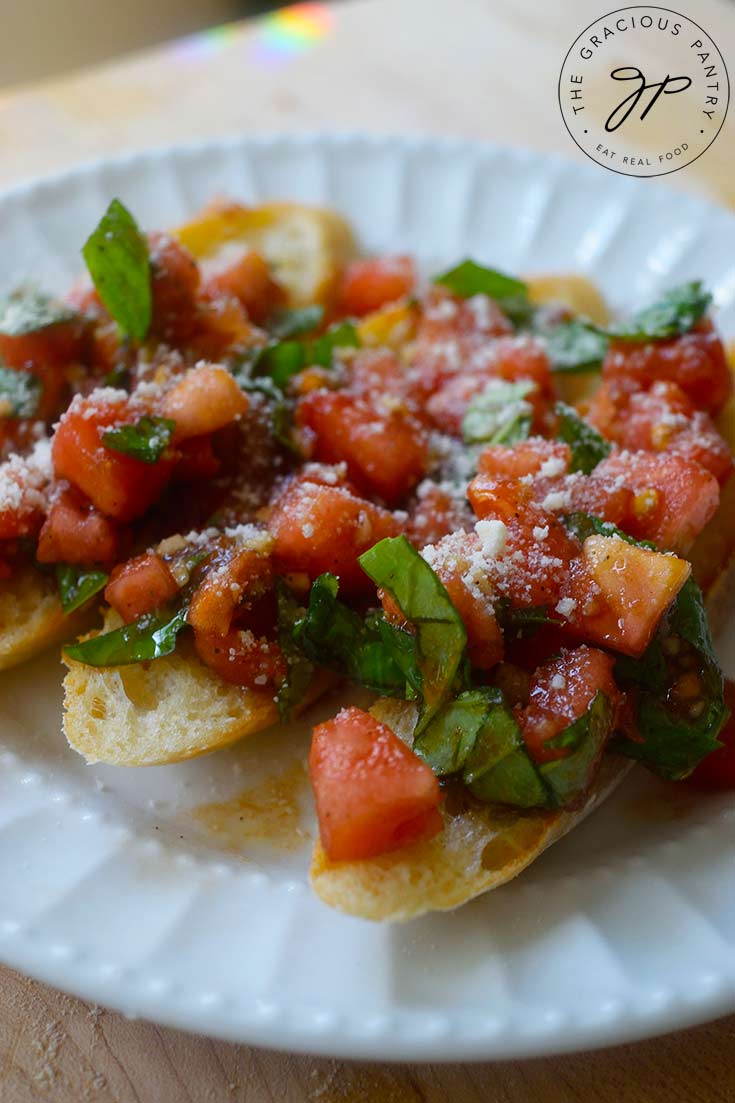 A side view of three Classic Bruschetta lined up on a white plate.