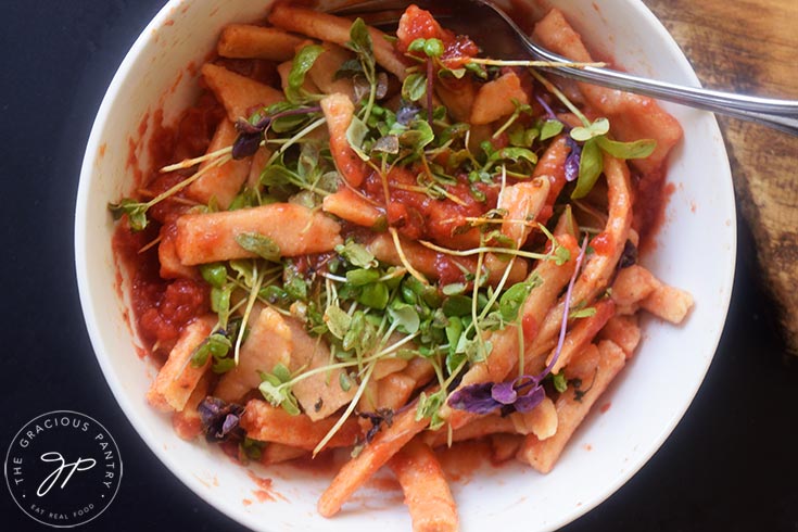 A bowl of Complete Protein Pasta topped with marinara and basil microgreens.