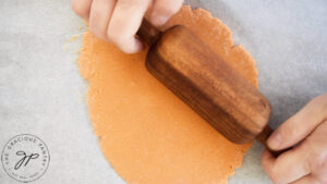 Complete protein pasta dough being rolled flat with a wood rolling pin.