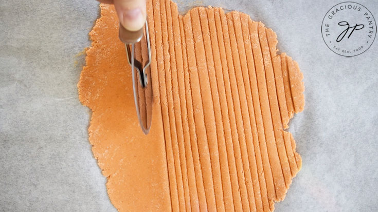 A pizza wheel cutting Complete Protein Pasta dough.