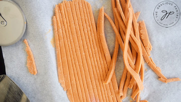 Cut Complete Protein Pasta dough lays cut on a piece of parchment.