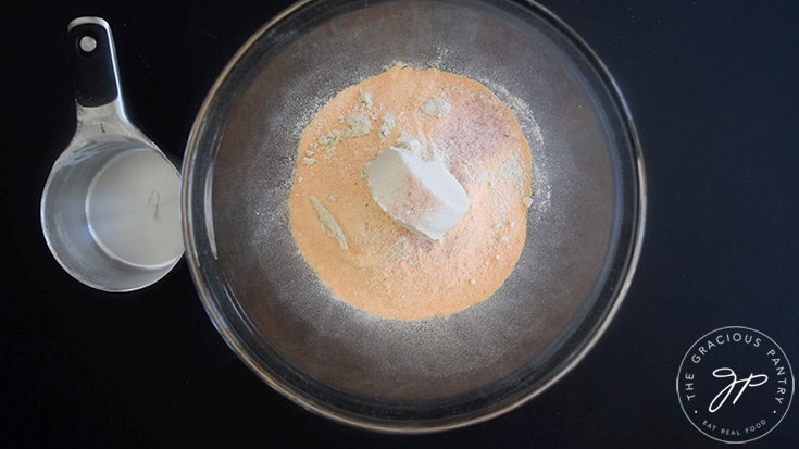 Red lentil flour, oat flour and salt sitting unmixed in a glass mixing bowl.