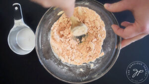 Blending water into red lentil flour mix with a wooden spoon.