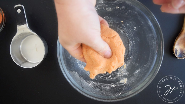 A hand holds a Complete Protein Pasta dough ball.