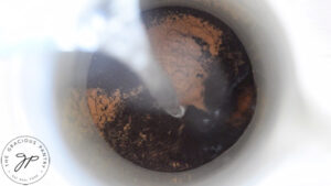 Hot water being poured into coffee grounds and pumpkin pie spice in a french press.