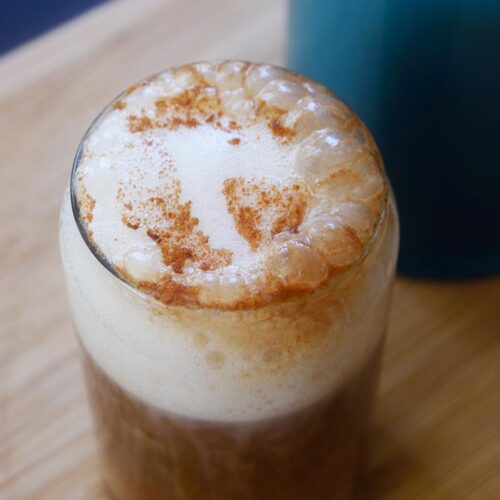 An angled view of a glass cup filled with a Healthy Pumpkin Spice Latte.