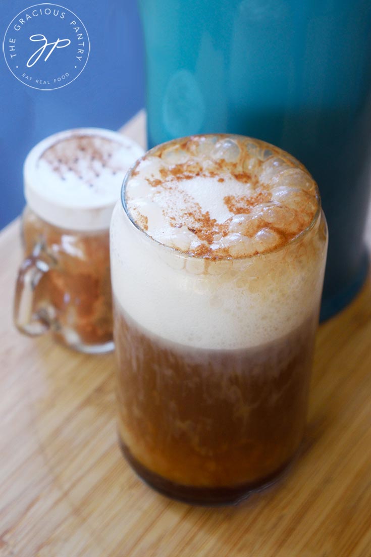 A side view of a just-poured, Healthy Pumpkin Spice Latte in a glass cup.