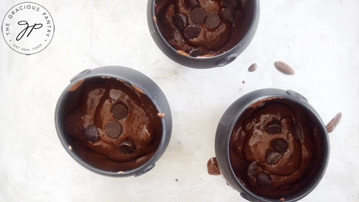 Three cauldron cakes sit on a baking pan, ready for the oven.