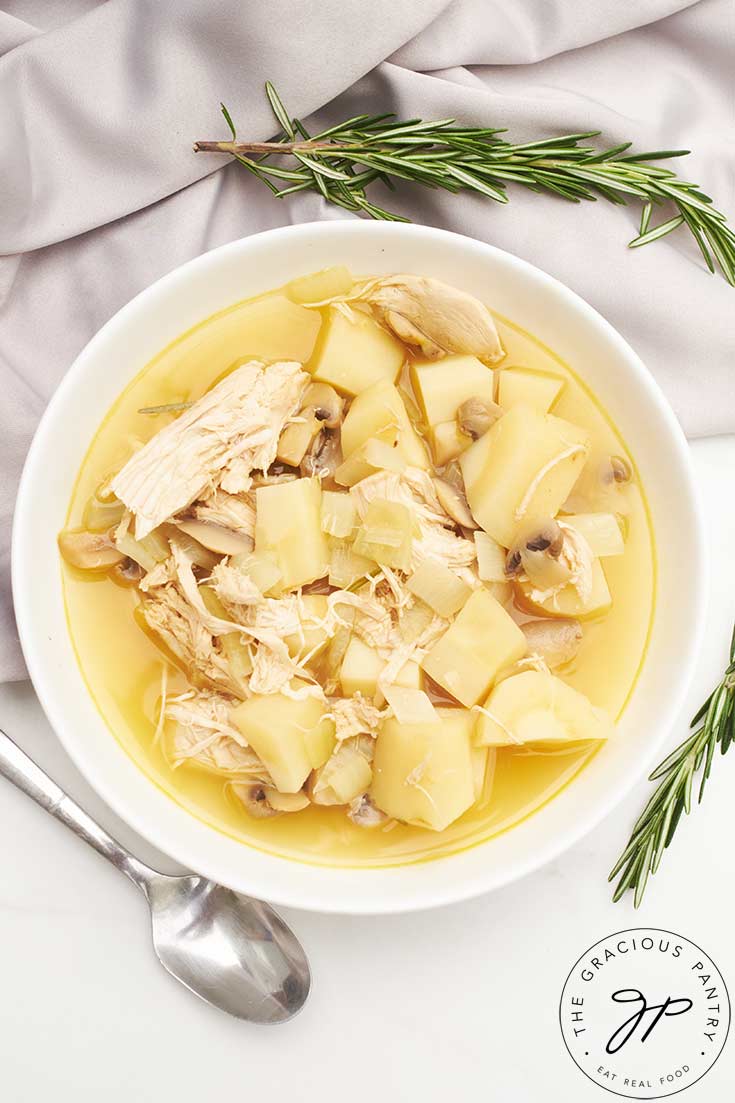 An overhead view of a white bowl filled with Chicken And Parsnip Soup.
