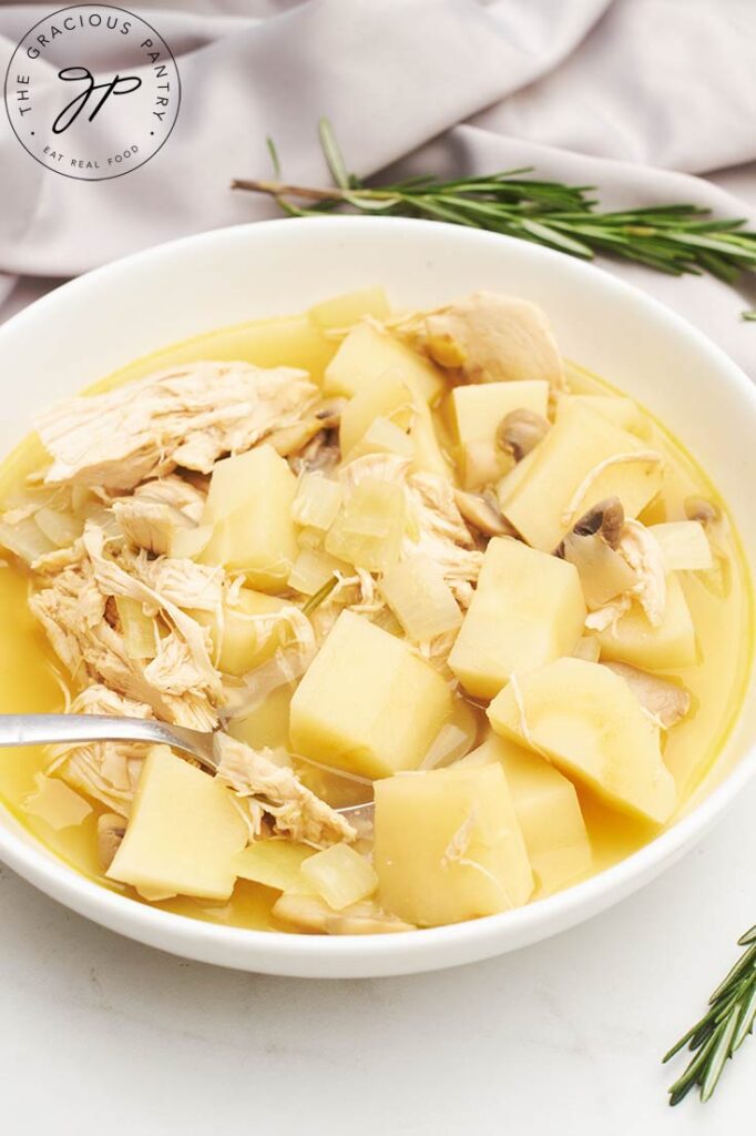 A side view of a white bowl filled with Chicken And Parsnip Soup.