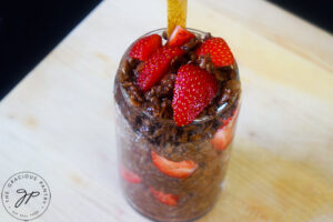 Layered chocolate oatmeal and strawberries in a glass with a wooden spoon.