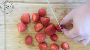 Chopping strawberries on a wooden cutting board.