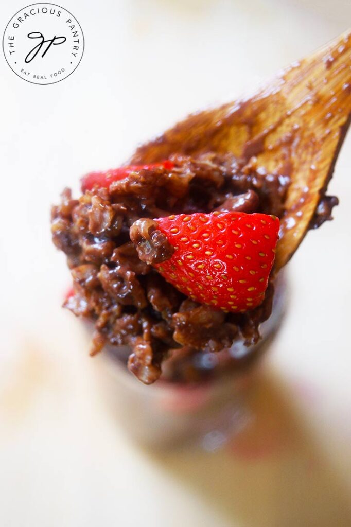 A wooden spoon lifting some Chocolate Oatmeal out of a full glass.