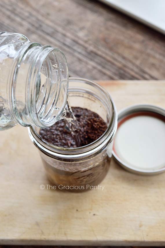 Pouring water into coffee grounds in a mason jar.