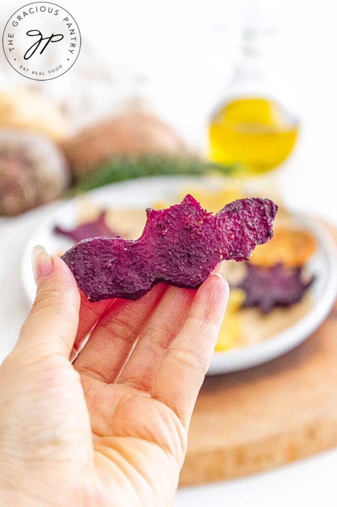 A woman's hand holds a bat-shaped roasted beet up for the camera.