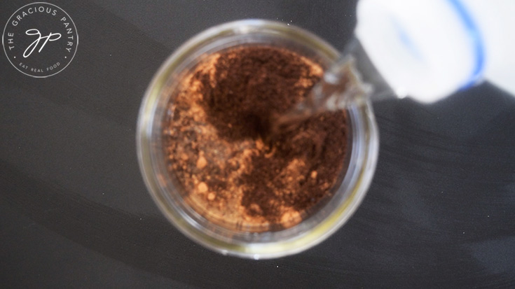 Pouring water into a canning jar with coffee grounds and pumpkin pie spice.