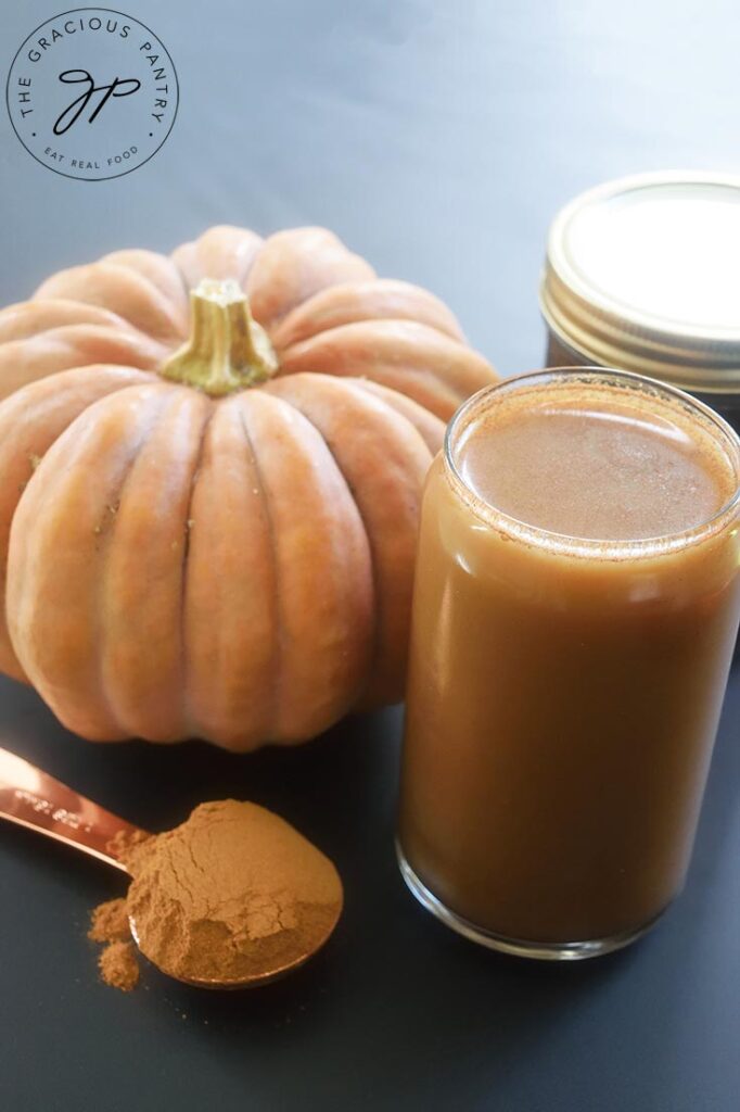 A front view of a glass of Pumpkin Spice Cold Brew Coffee sitting next to a pumpkin.